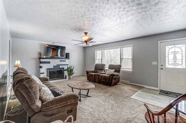 carpeted living room featuring a textured ceiling, ceiling fan, a fireplace, and a wealth of natural light