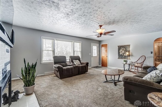 living room featuring carpet floors, a fireplace, arched walkways, and a textured ceiling