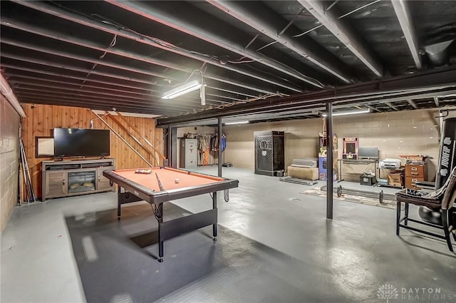 unfinished basement featuring concrete block wall, wooden walls, and water heater