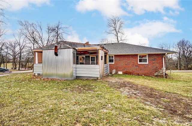 back of property featuring roof with shingles, brick siding, and a lawn