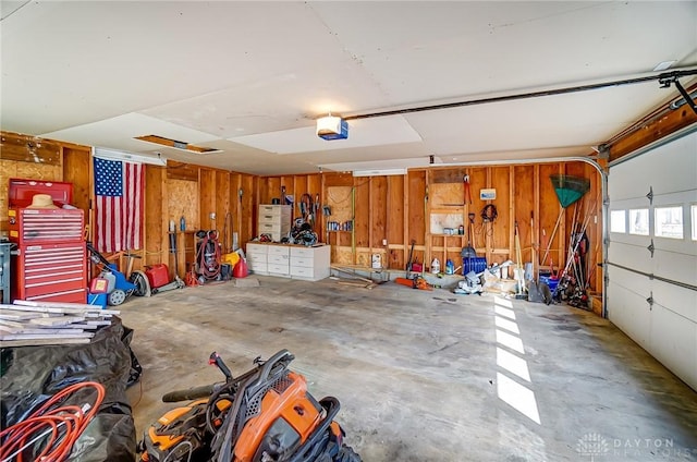 garage with wooden walls, a workshop area, and a garage door opener