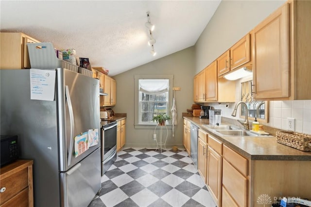 kitchen with light floors, stainless steel appliances, light brown cabinets, vaulted ceiling, and a sink