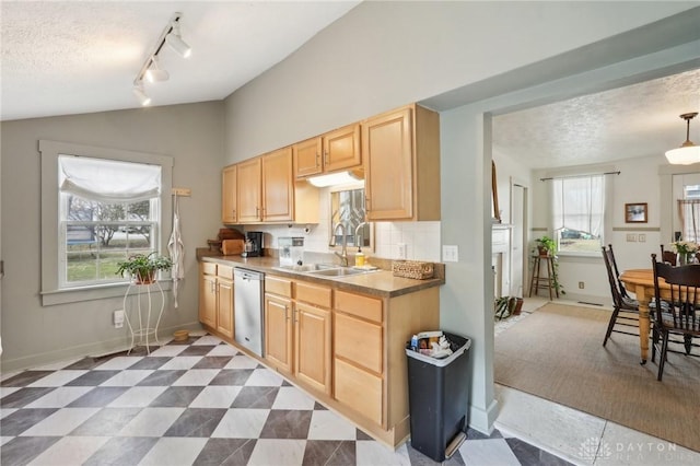 kitchen with light brown cabinetry, vaulted ceiling, a textured ceiling, a sink, and dishwasher