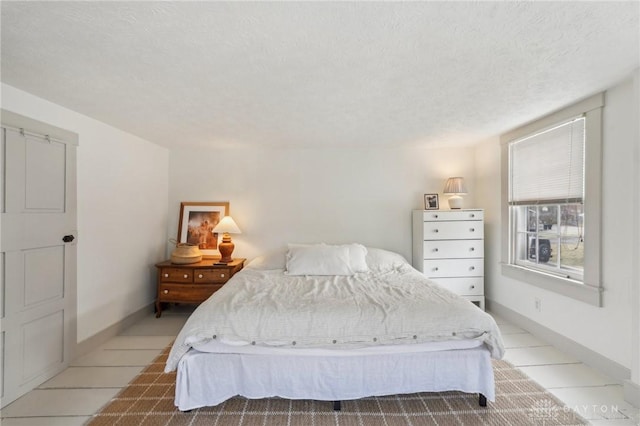 bedroom with a textured ceiling, light tile patterned floors, and baseboards