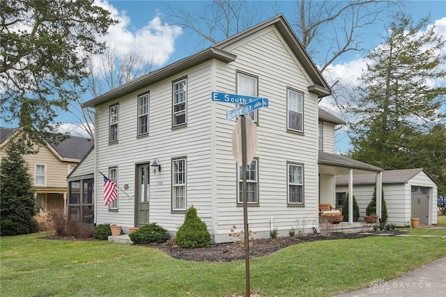 view of front facade featuring a garage, a front yard, and an outdoor structure