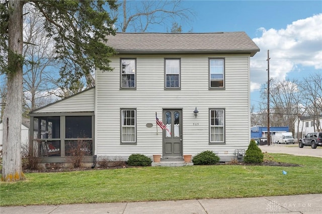 view of front of property featuring a sunroom, roof with shingles, and a front lawn