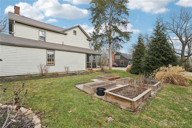 view of yard with a sunroom and a vegetable garden