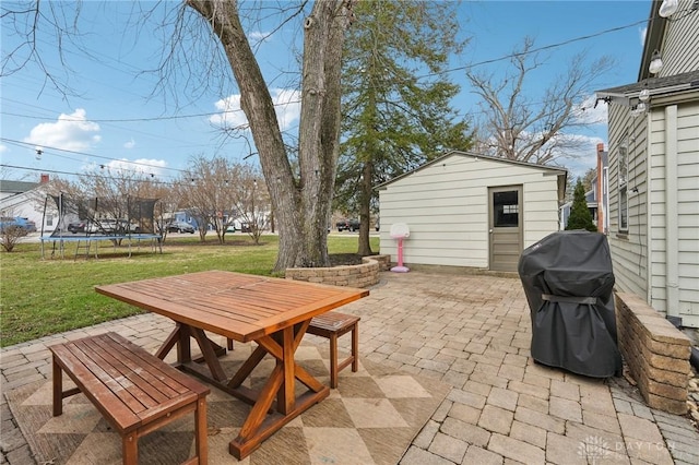 view of patio with outdoor dining space, a trampoline, area for grilling, and an outdoor structure