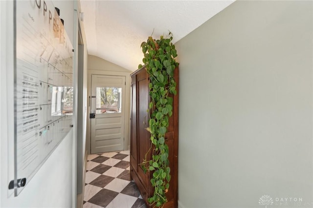 hall featuring lofted ceiling, a textured ceiling, and tile patterned floors