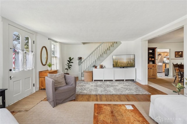 living room with stairs, a textured ceiling, and wood finished floors