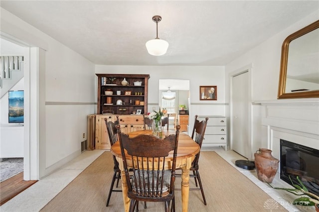 dining room featuring a fireplace with flush hearth and stairs