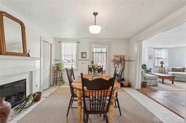 dining area with a textured ceiling and a glass covered fireplace