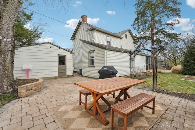 back of property featuring an outbuilding, a yard, a chimney, and a patio area