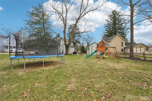 view of yard featuring a trampoline, a residential view, a playground, and fence