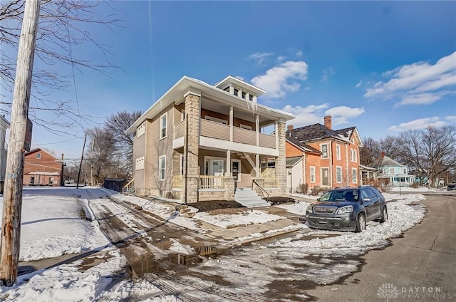 american foursquare style home with covered porch, a residential view, and a balcony