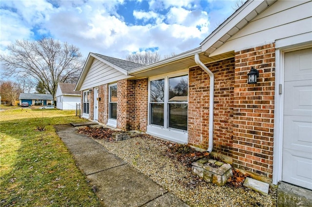 view of property exterior with a garage, brick siding, and a lawn