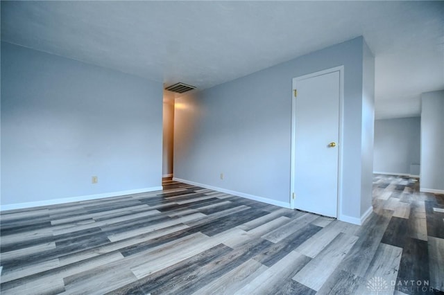 empty room featuring wood finished floors, visible vents, and baseboards