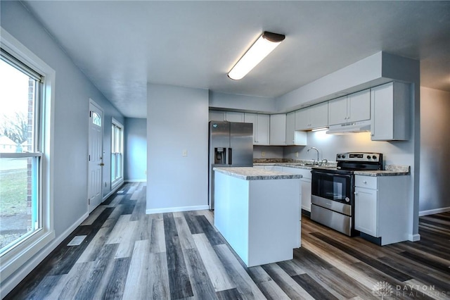 kitchen featuring appliances with stainless steel finishes, dark wood-style flooring, a center island, under cabinet range hood, and white cabinetry