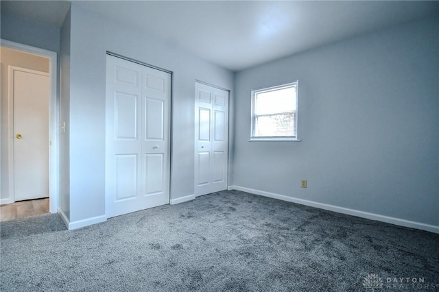 unfurnished bedroom featuring multiple closets, carpet floors, and baseboards