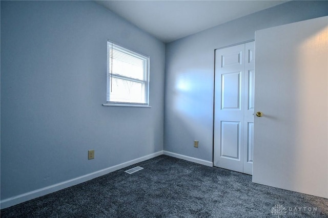 empty room with baseboards, visible vents, and dark carpet