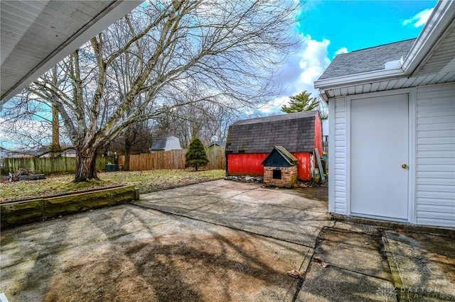 view of patio / terrace featuring fence, a storage unit, and an outdoor structure