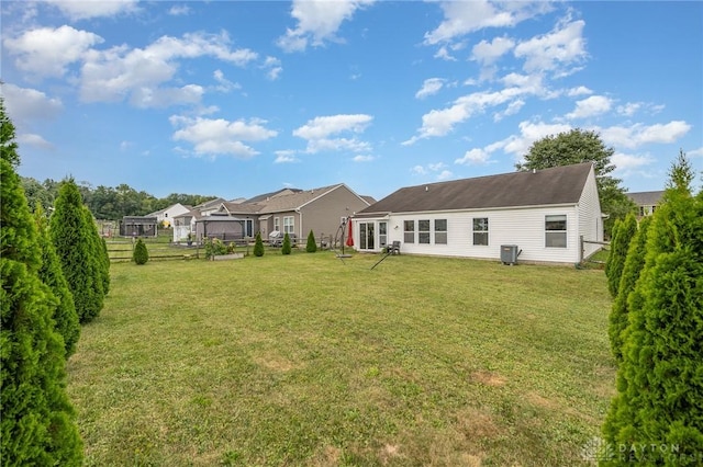 back of property featuring a lawn, cooling unit, and fence