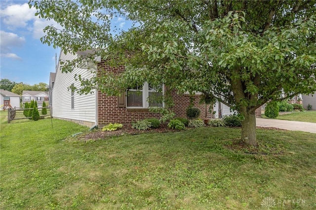 view of front of home with a front yard, concrete driveway, and brick siding