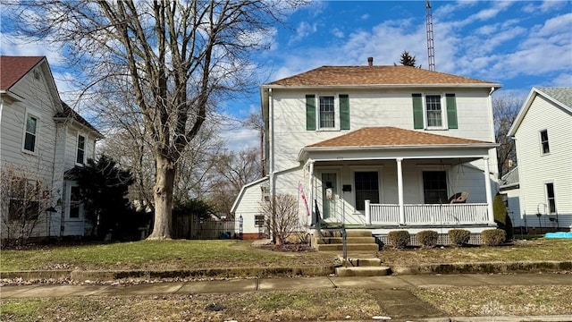 view of front of property with a porch, a front lawn, and roof with shingles