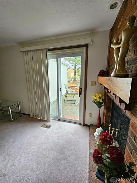 entryway with a brick fireplace, visible vents, and carpet floors