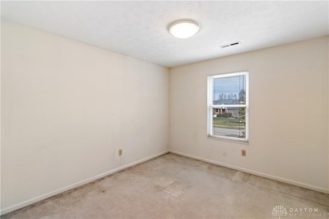 empty room with visible vents, light carpet, and baseboards