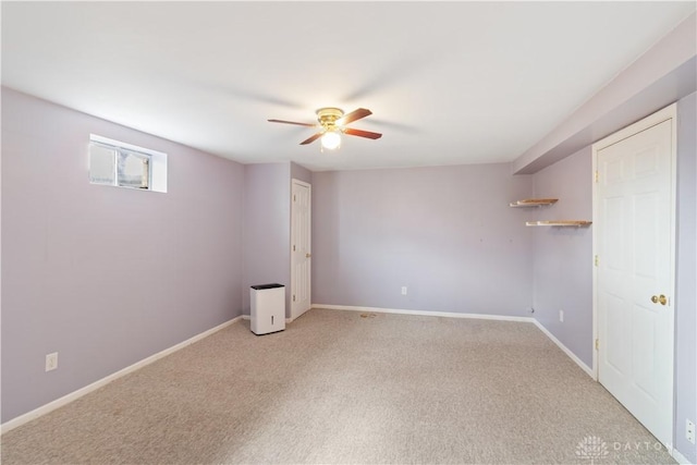 spare room featuring ceiling fan, baseboards, and light colored carpet