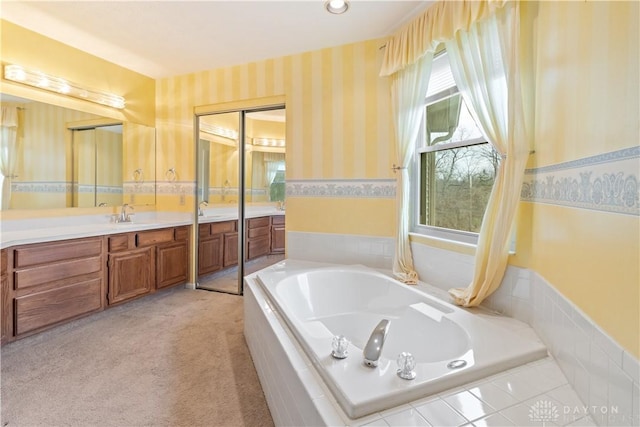 bathroom with a garden tub, vanity, and wallpapered walls