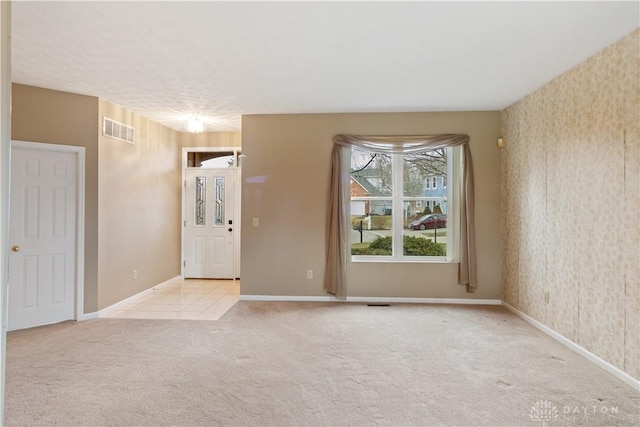 empty room with wallpapered walls, baseboards, visible vents, and carpet flooring