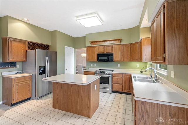 kitchen featuring stainless steel appliances, light countertops, brown cabinetry, a sink, and a kitchen island