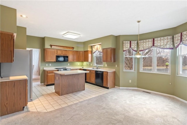 kitchen with black appliances, a kitchen island, light countertops, and light colored carpet