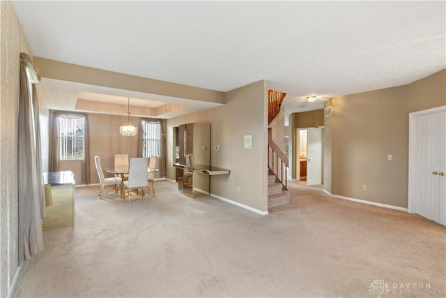 unfurnished room featuring a raised ceiling, stairway, carpet flooring, a chandelier, and baseboards