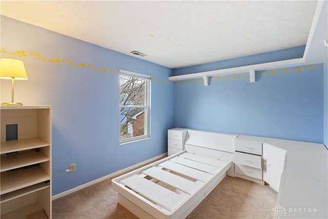 unfurnished bedroom with baseboards, a textured ceiling, visible vents, and light colored carpet