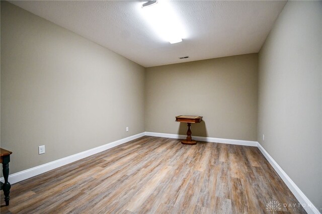 empty room with baseboards, a textured ceiling, visible vents, and wood finished floors