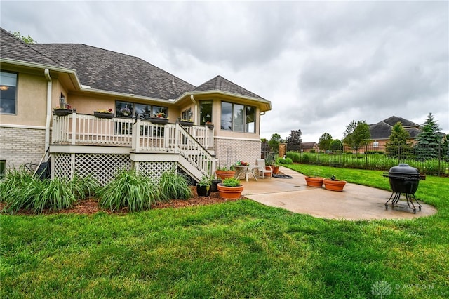 back of property featuring brick siding, a patio, stucco siding, a lawn, and fence