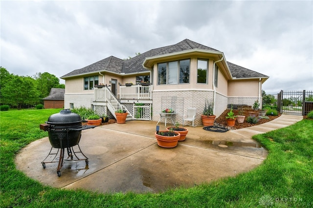 rear view of house with brick siding, a patio, stucco siding, a shingled roof, and a lawn