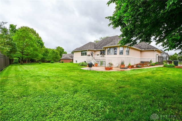 back of property featuring stucco siding, fence, a lawn, and a patio