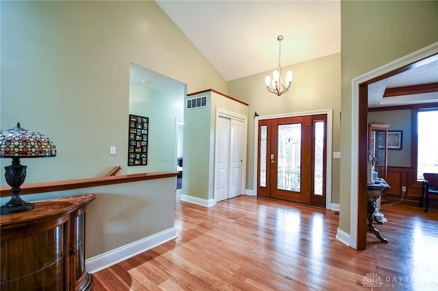 entrance foyer featuring a notable chandelier, visible vents, wood finished floors, high vaulted ceiling, and baseboards