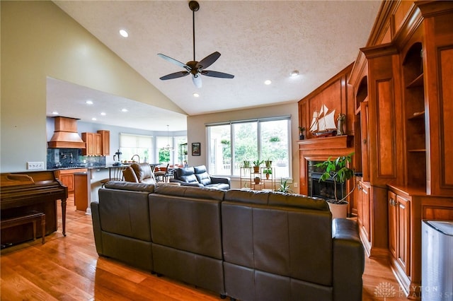 living area featuring a ceiling fan, wood finished floors, a textured ceiling, a fireplace, and recessed lighting