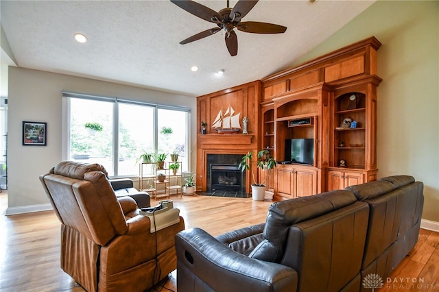 living area with light wood-style floors, a premium fireplace, baseboards, and a textured ceiling