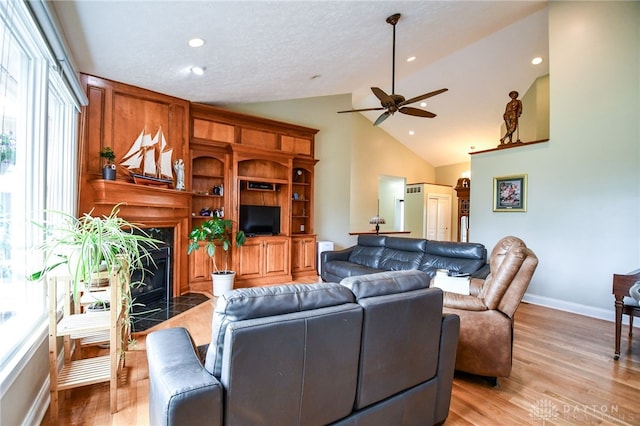 living area with ceiling fan, baseboards, a high end fireplace, and light wood-style floors