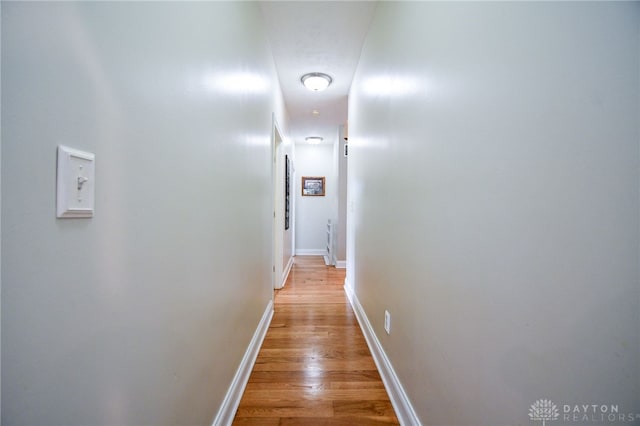 hall with light wood-style flooring and baseboards