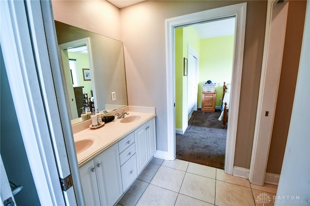 bathroom featuring tile patterned flooring, a sink, ensuite bathroom, and double vanity