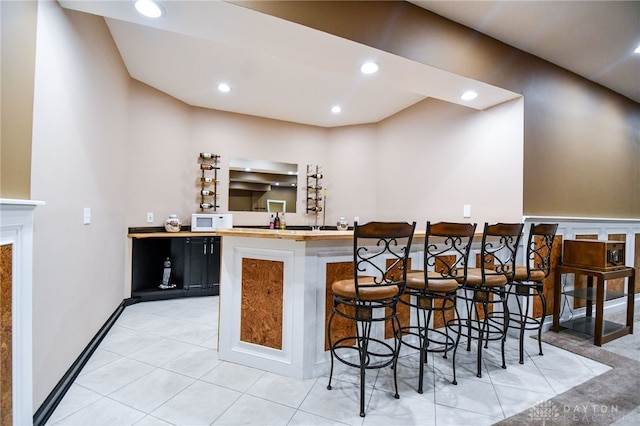 bar featuring light tile patterned floors, white microwave, bar area, and recessed lighting