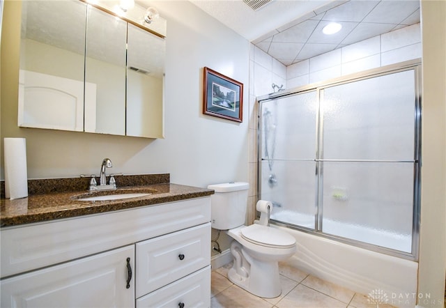 full bathroom with visible vents, toilet, shower / bath combination with glass door, tile patterned flooring, and vanity