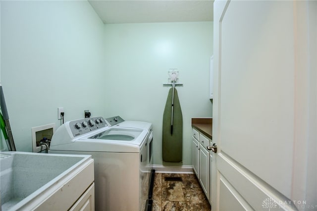 laundry area featuring washing machine and dryer, cabinet space, a sink, and baseboards